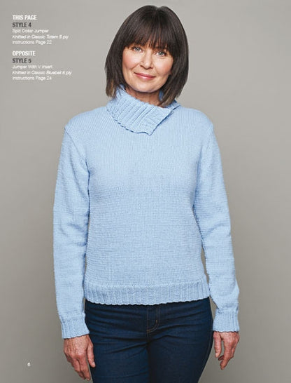 A woman in a light blue sweater and jeans stands against a gray background. She smiles softly, exuding a warm and cozy mood.