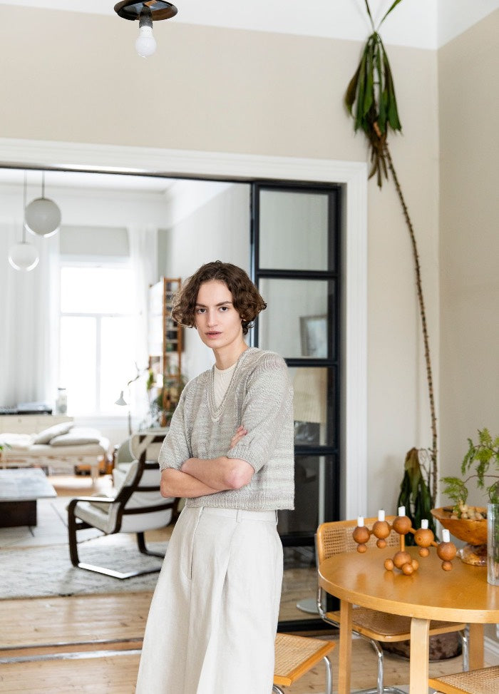 Mesclada Sweater: light-colored knit sweater worn with high-waisted pants, photographed in a bright modern living space with natural light.