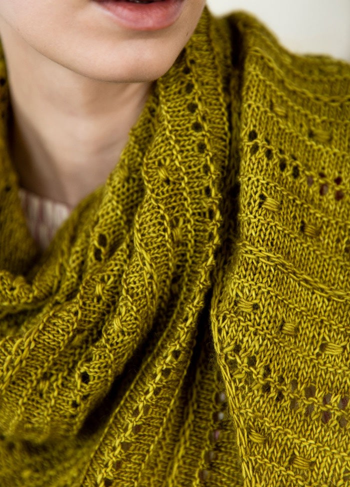 Rendado Shawl: green knit shawl with eyelets and textured stitch patterns, photographed in a close-up view.