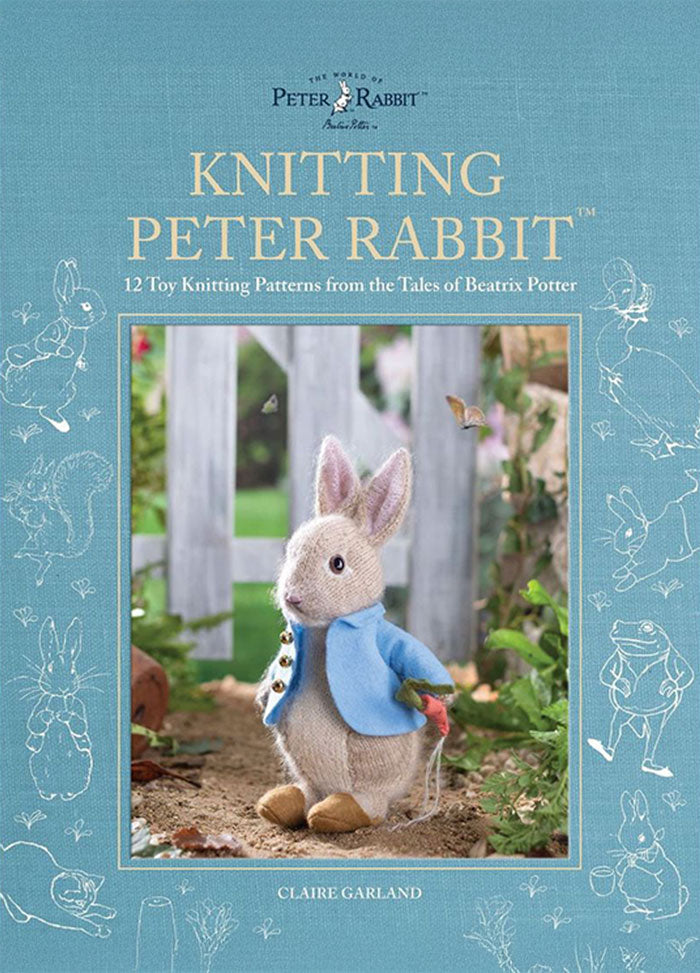 Cover of “Knitting Peter Rabbit” by Claire Garland, featuring a knitted Peter Rabbit toy in a blue jacket standing outdoors near greenery and a wooden fence. The subtitle reads “12 Toy Knitting Patterns from the Tales of Beatrix Potter,” with a blue background adorned with white illustrations from Beatrix Potter’s stories.