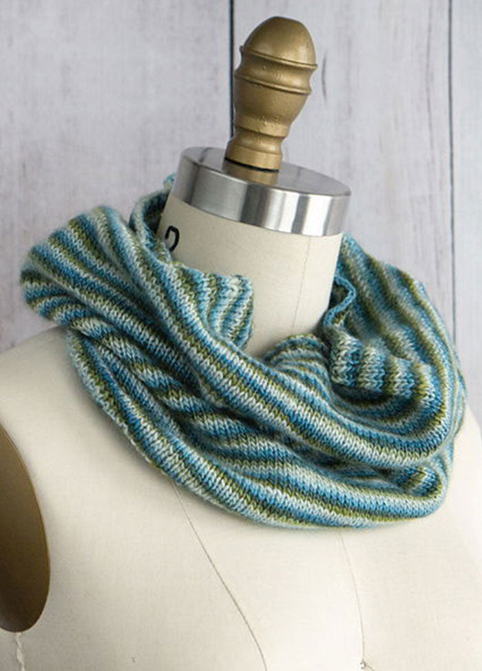 Pirouette Cowl on mannequin, hand-knit in alternating blue and green stripes with a soft, smooth texture.