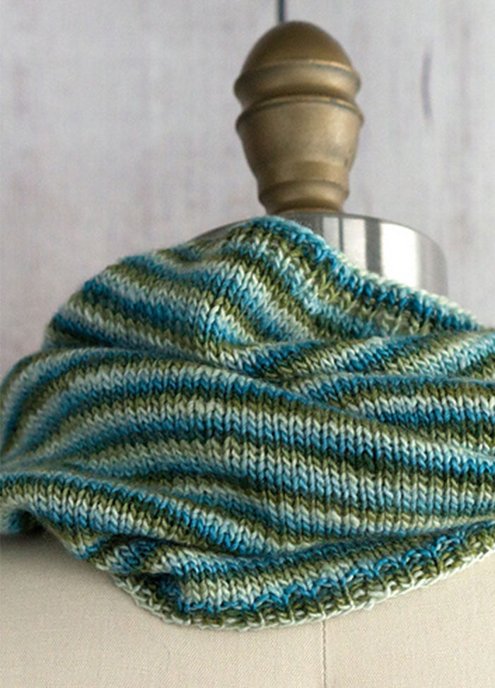 Pirouette Cowl on mannequin, hand-knit in soft blue and green stripes with a smooth, cozy texture.