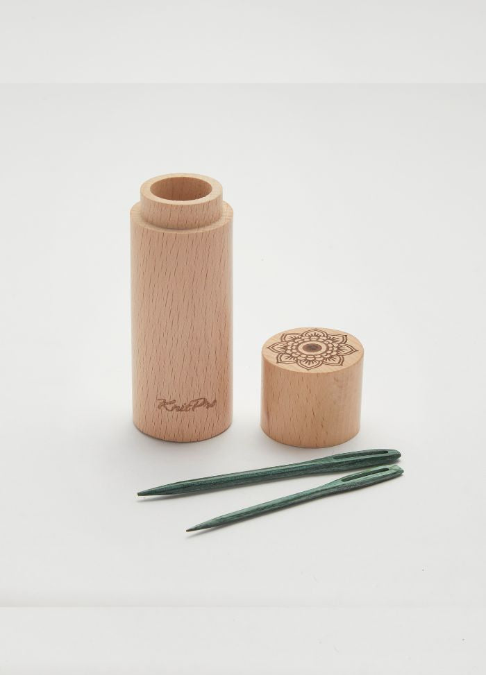 Wooden container with a teal floral design, holding two small and two large darning needles for yarn crafting.