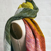 Rainbow Showers Scarf draped on mannequin, hand-knit with a gradient of green, yellow, pink, red, and orange.