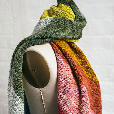 Rainbow Showers Scarf draped on mannequin, hand-knit with a gradient of green, yellow, pink, red, and orange.