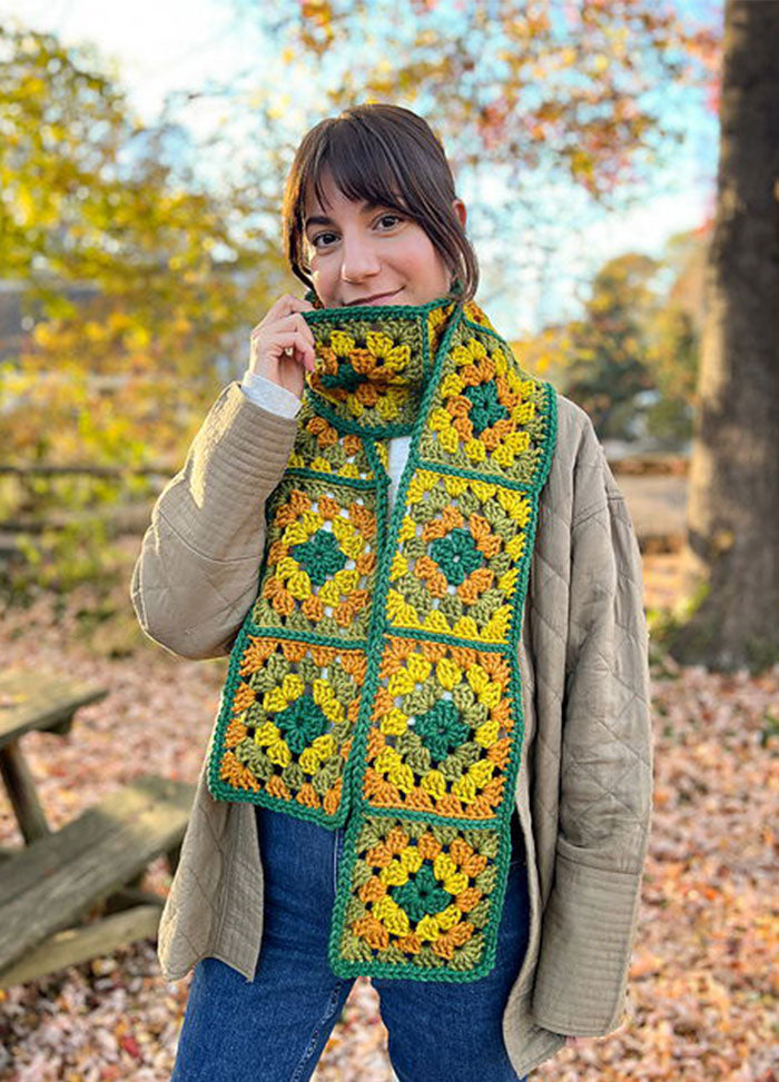 Retro Cardo Scarf worn outdoors, crocheted in granny squares with green, yellow, and orange tones.