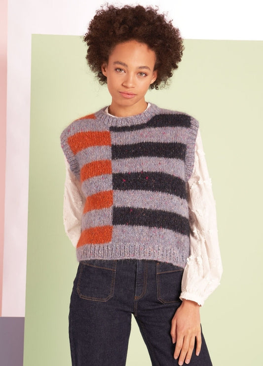 A person with curly hair wears a knitted vest with orange and gray stripes over a white blouse. The background is split into soft pastel colors, creating a modern, stylish look.