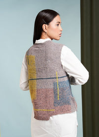 A person with long dark hair wears a textured, multicolored vest over a white shirt, facing away. The background is light blue with a dark curtain.