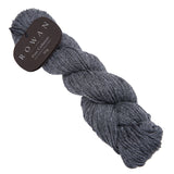 A skein of soft grey cashmere yarn with a tag, showcasing its luxurious texture and delicate colour flecks.