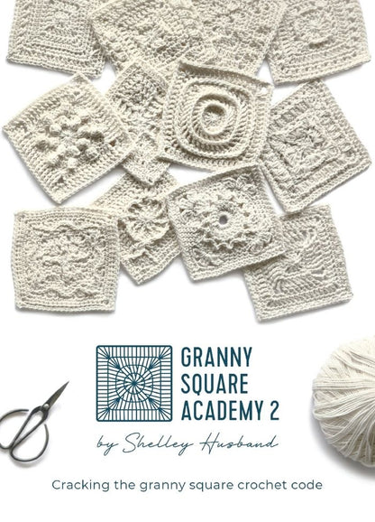 A collage of intricate white crocheted granny squares is displayed above text reading "Granny Square Academy 2 by Shelley Husband." A yarn ball and scissors are seen below, suggesting a crafting theme.