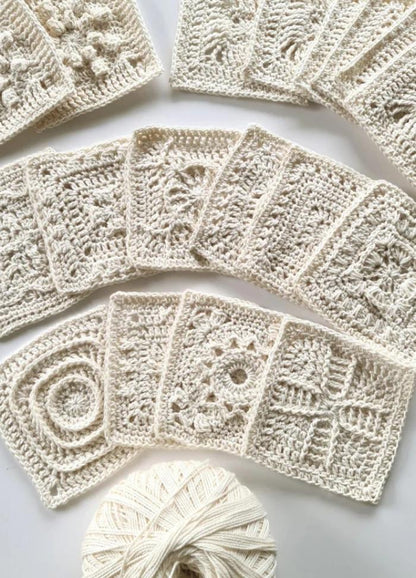 A collection of intricately crocheted white square patterns displayed in a fan shape, with a ball of matching yarn at the bottom, conveying craftsmanship and creativity.