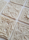 Intricate crochet squares laid out on a flat surface, each with unique patterns of lace-like loops and geometric designs, evoking a sense of elegance.