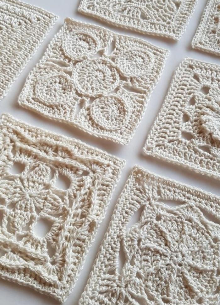 Intricate crochet squares laid out on a flat surface, each with unique patterns of lace-like loops and geometric designs, evoking a sense of elegance.