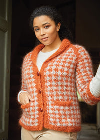 A person poses confidently in a cozy, orange and white checkered knit cardigan with large buttons, conveying warmth and style.