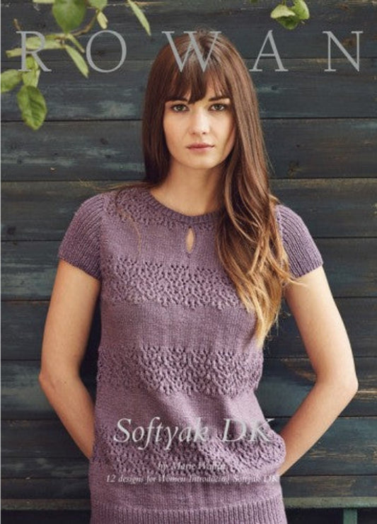 Cover image of the Rowan Softyak DK knitting pattern collection by Marie Wallin, featuring a model wearing a short-sleeved purple knitted top with a keyhole neckline, set against a dark blue wooden background. Includes text: '12 designs for Women using Softyak DK'.
