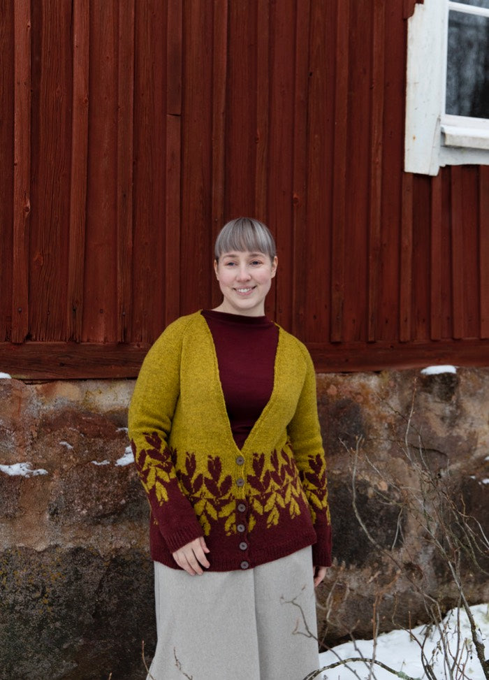 Berry Bushes Cardigan: mustard yellow knit with maroon berry bush motifs on hem and sleeves, styled with maroon top and grey pants.