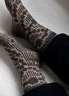 Grandma's Pearls Socks: gray and beige knit socks with vertical stripes and pearl-like circular motifs, worn with black pants.