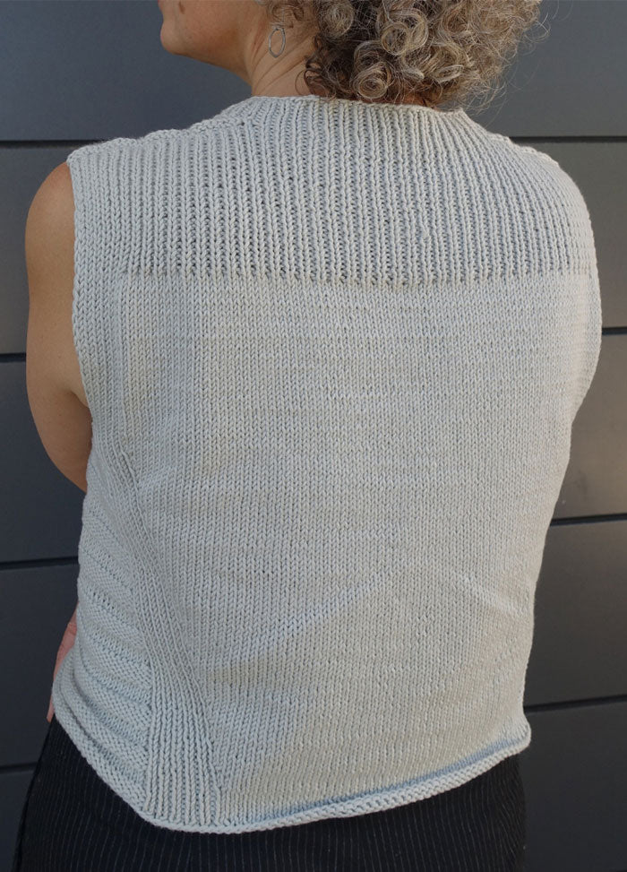 Sleeveless Summer Esio Top in a soft neutral tone, hand-knitted with lightweight yarn. Features ribbed trim at neckline and armholes, perfect for warm-weather layering or standalone wear.
