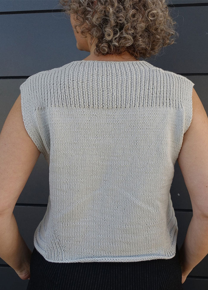 Lightweight knitted Summer Esio Top in a sleeveless design, featuring ribbed edges and a clean silhouette. Ideal for warm-weather outfits, styled with dark trousers for a modern casual look.