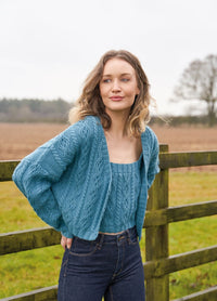 Cropped cable cardigan with relaxed drop shoulders, gentle V-neck and three-button closure; worked in Alpaca Soft DK; designed to twin with Wilson - Cropped cabled vest with straightforward rectangular shaping, ribbed borders and straps; soft handle in Alpaca Soft DK; layers with Tammi.