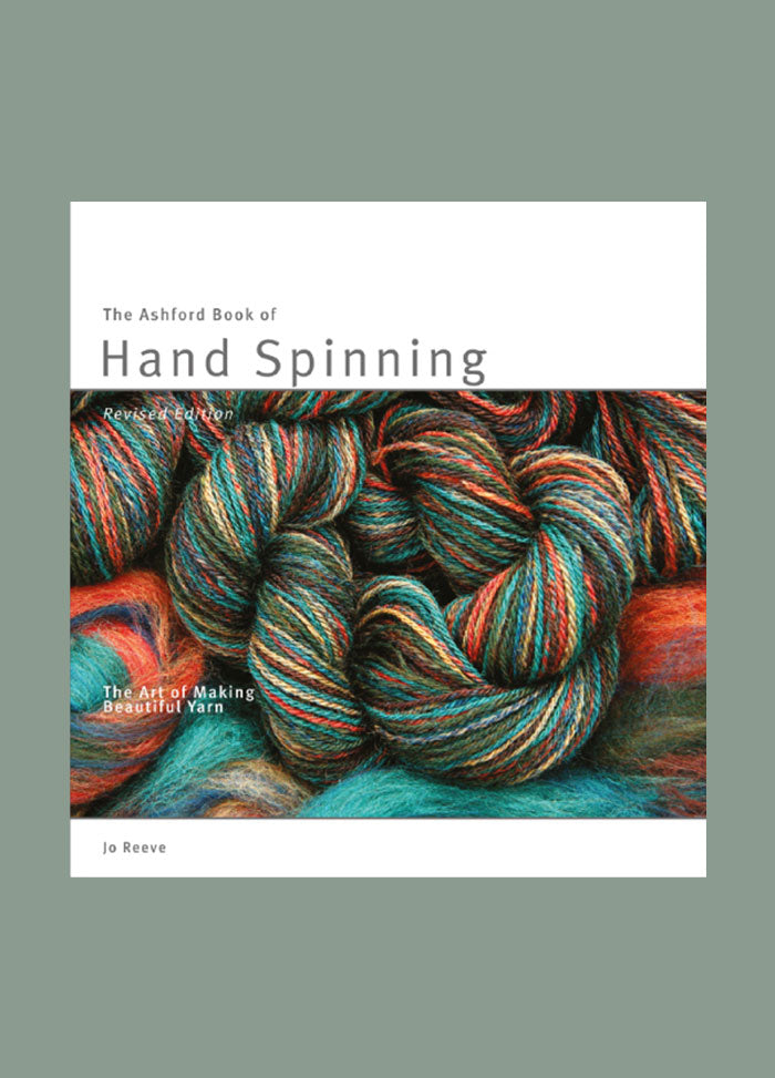 Cover of The Ashford Book of Hand Spinning by Jo Reeve, featuring a close-up of hand-spun, multicoloured yarn skeins in rich teal, rust, and earthy tones, with the title in clean, uppercase lettering against a white border.