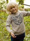 Child in light gray Tiger Sweater with tiger face motif, outdoors with plants.