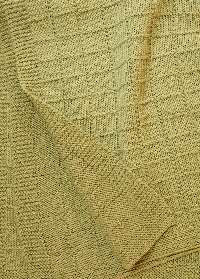 Close-up of Window Pane Blanket in light green, featuring a textured knit with raised square panels.