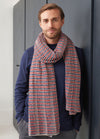 A man wearing a cozy, multicolored striped scarf, showcasing intricate knit patterns and a soft texture