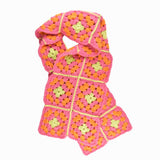 A crocheted scarf featuring a vibrant pink and green design, showcasing intricate patterns and textures.