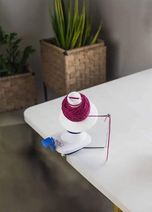 A white table , featuring a hand-operated yarn winder for knitting and crochet projects.
